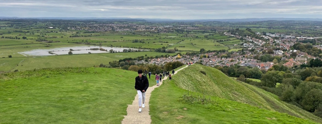 Landschaft in Devon bei einem Ausflug während der Sprachreise nach Exeter Mehrere Personen steigen auf einen Hügel mit Blick auf Exeter und die Landschaft in Devon