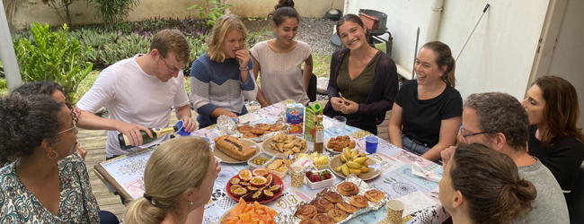 Mehrere Sprachreiseteilnehmer genießen ein reichhaltiges Frühstück mit tropischen Früchten und Gebäck auf La Réunion