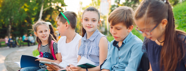 Mädchen und Jungen sitzen draußen und lernen Englisch gemeinsam während einer Sprachreise für Schüler in Box Hill