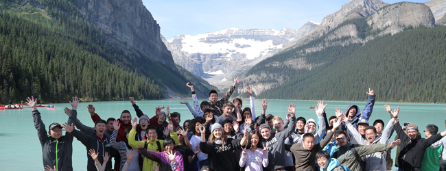 Schüler winken in die Kamera vor der Bergkulisse der Rocky Mountains bei einer Sprachreise in Calgary